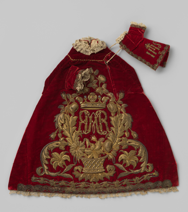 Ein roter Samtmantel mit goldener Stickerei und einer Krone, der aufwendige Designs zeigt, vor einem weißen Hintergrund.