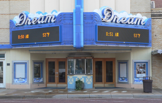 Außenansicht des Dream Theaters in St. Louis, Missouri, mit Glastüren und -fenstern, einem Namen-Schild, einem Müllbehälter, einem Topf mit einer Pflanze und einer Straße im Vordergrund.