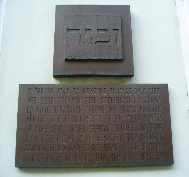 Metallplatte mit hebräischer Schrift an der Seite eines Gebäudes angebracht, wahrscheinlich ein Denkmal für die jüdische Gemeinde.