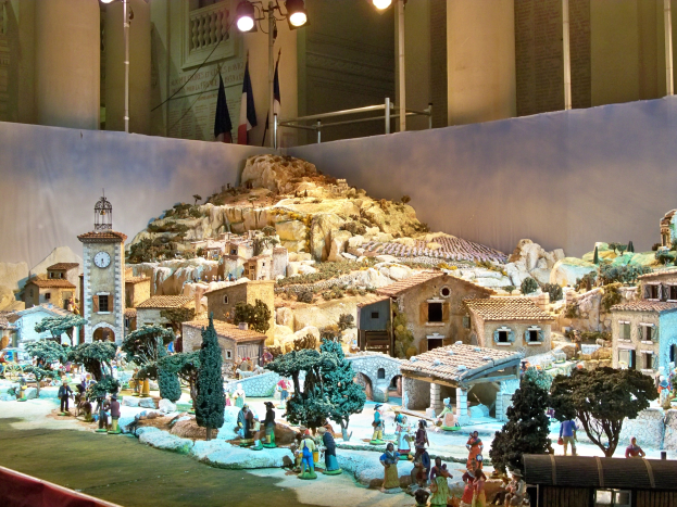 Ein detailliertes Miniatur-Weihnachtskrippen-Diorama in einem Museum, mit Figuren, Strukturen und Beleuchtungselementen.