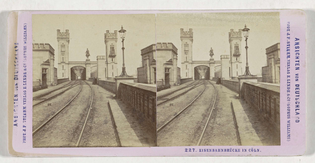 Schwarz-weißes stereoskopisches Bild einer Eisenbahnbrücke in Köln, Deutschland, mit Eisenbahnschienen, Wänden, Pfählen, Statuen, Himmel und Text.