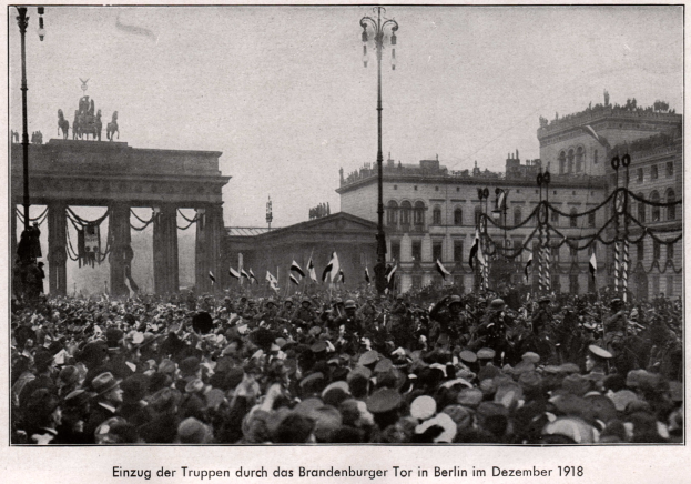 Große Menschenmenge vor dem Brandenburger Tor in Berlin, Deutschland, 1918, mit Hüten und Fahnen, vor dem Tor mit Säulen und Statuen im Hintergrund.