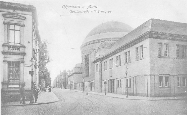 Schwarzes und weißes Foto einer Stadtstraße mit der Beschriftung "Offenbach a.M., Goethestraße mit Synagoge", das Gebäude, Straßenlaternen, Bäume und Fußgänger zeigt.