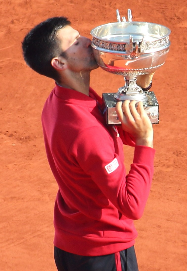 Novak Djokovic feiert mit dem French-Open-Pokal nach seinem Sieg gegen Rafael Nadal im Finale der Herren-Einzel, indem er den Pokal hält und ihn triumphierend küsst.