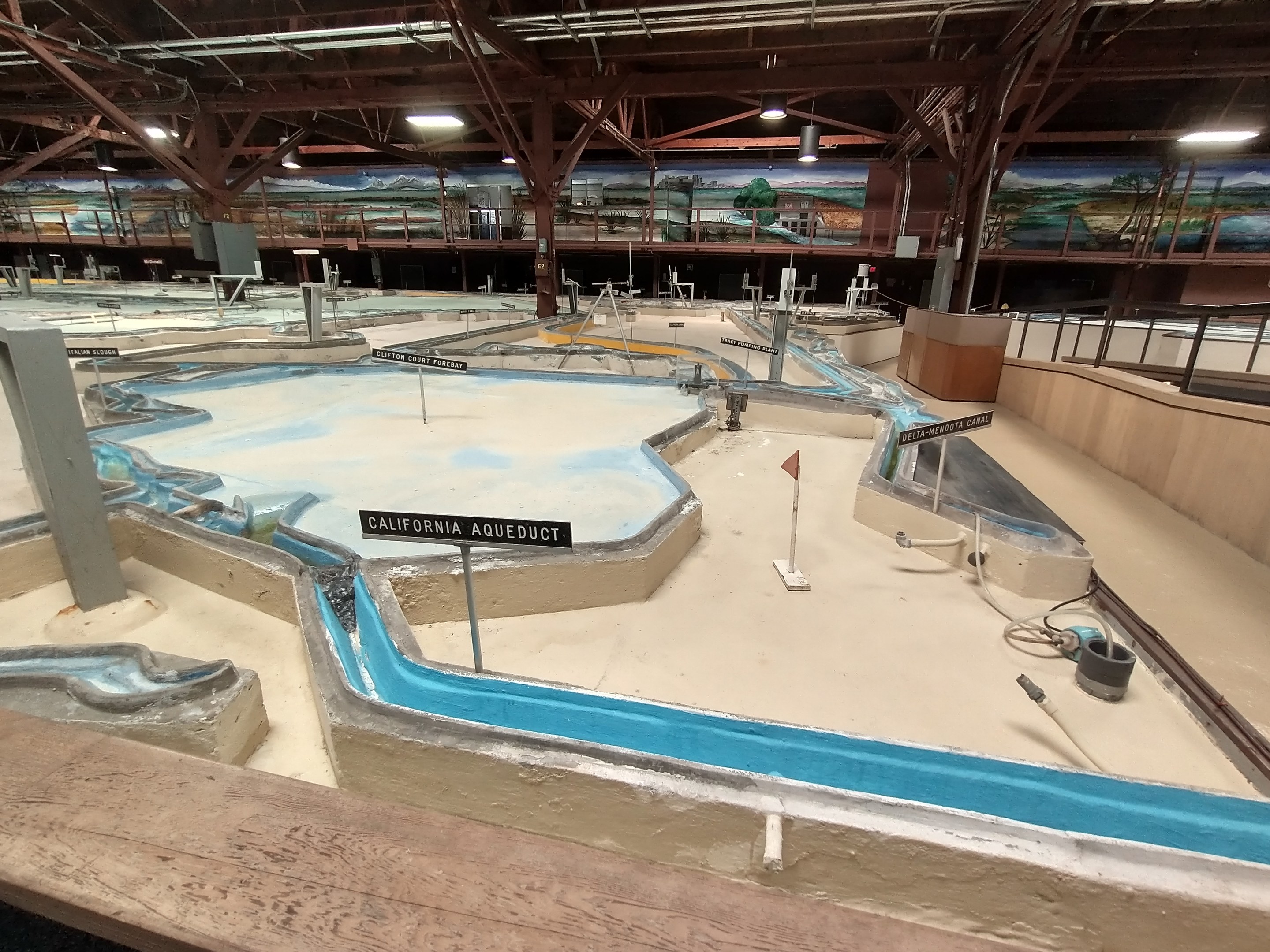 Großer Indoor-Wasserpark mit mehreren Wasserrutschen, Deckenleuchten, Wandgemälden und einem Minigolfplatz.