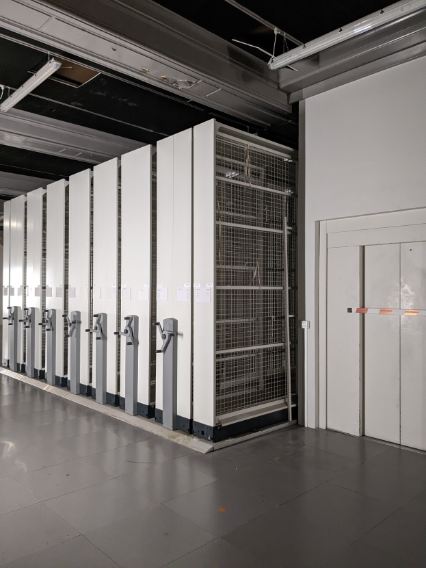 Ein großer Raum voller Numerous Server, mit einem Boden, einer Wand auf der rechten Seite und einer Decke mit Leuchten oben, der wie ein Rechenzentrum aussieht.