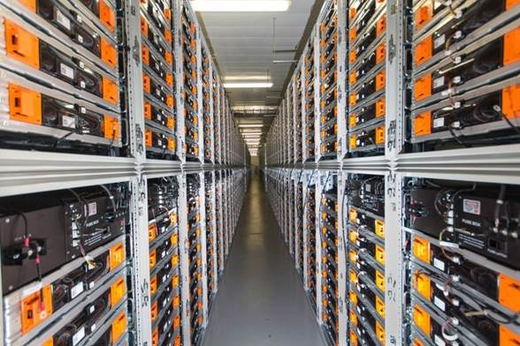 Eine lange Reihe von Servern in einem Rechenzentrum, mit elektronischen Geräten in den Räckern und Lichtern oben.