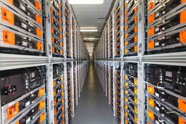 Eine lange Reihe von Servern in einem Rechenzentrum, mit elektronischen Geräten in den Räckern und Lichtern oben.