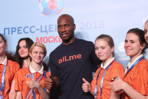 Eine Gruppe von Menschen auf einer Bühne mit einem Mann in der Mitte, der ein Mikrofon hält, hinter einem Banner mit dem Text und Logo der FIFA WM 2018 Russland.