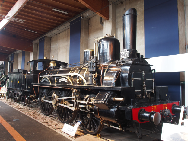 Alte Dampflokomotive in einem Museums Setting mit umgebenen Eisenbahnschienen und Informationsschildern.