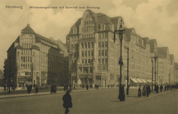 Ein altes Schwarz-Weiß-Foto von Menschen, die auf einer bewölkten Straße in Hamburg, Deutschland, entlanggehen, gesäumt von Gebäuden, Straßenlaternen, Autos und Text oben.