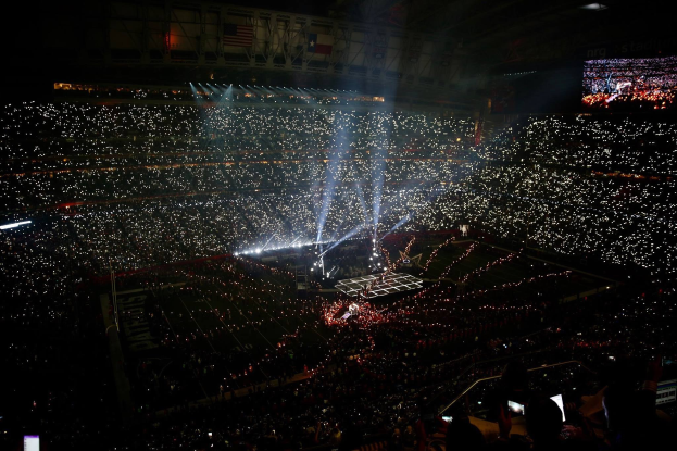 Große Menschenmenge in einem hell erleuchteten Stadion bei Nacht mit einem Bildschirm, der die Ergebnisse der Super Bowl XLVII-Halbzeitshow auf der rechten Seite anzeigt.