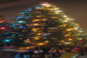 Ein geschmückter Weihnachtsbaum mit Menschenfiguren auf einem Tisch darunter.